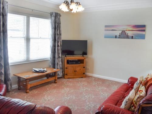 a living room with a couch and a table and a tv at Courtyard View in Keswick