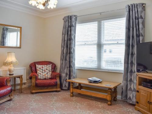 a living room with a tv and two chairs and a table at Courtyard View in Keswick