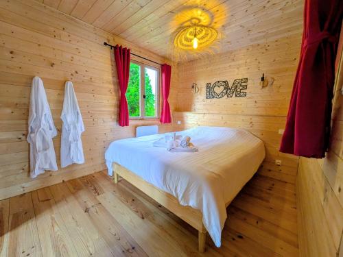 a bedroom with a bed in a log cabin at Le Coquelicot - Châlet avec SPA in Trainel