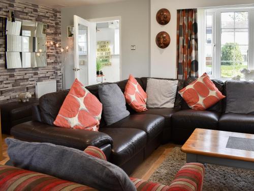 a living room with a leather couch and a table at Mountain View in Morfa Bychan