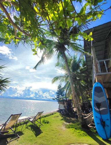a blue surfboard sitting on the grass next to a beach at Reggae Vibes De Romblon in Agpanabat