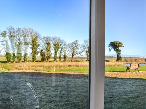 a window view of a park with a bench at The Foldyard - Uk46004 in Rotsea