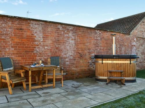 a patio with a wooden table and a hot tub at The Foldyard - Uk46004 in Rotsea