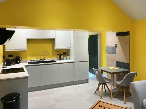 a kitchen with white cabinets and a table with chairs at Peartree Cottage in Sheffield