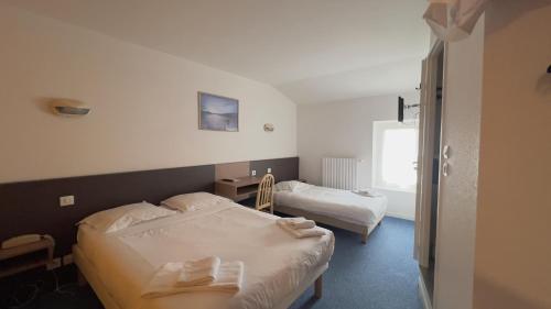 Una habitación de hotel con dos camas y una ventana. en Hôtel le Relais de Vendée, en Les Herbiers