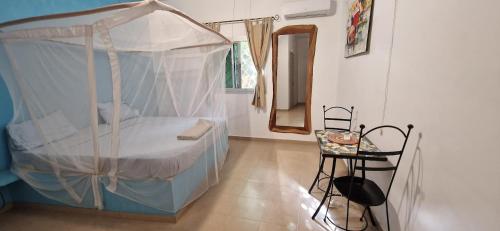 a bedroom with a canopy bed and a table at Villa Saraba in Somone