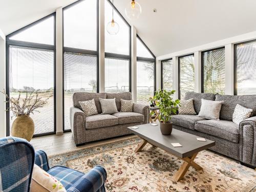 ein Wohnzimmer mit Sofas und einem Tisch und Fenstern in der Unterkunft Bay Tree Cottage - Uk35891 in Ludchurch