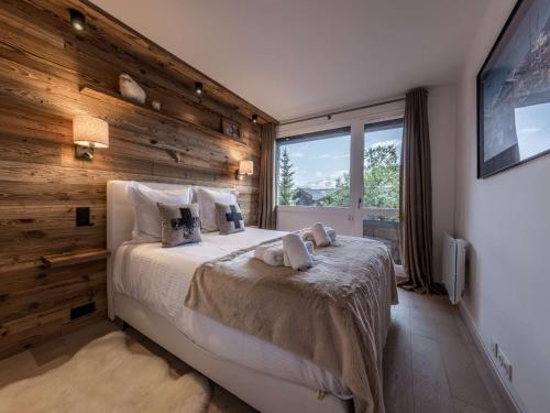 ein Schlafzimmer mit einem Bett mit einer Holzwand in der Unterkunft Courchevel 1850 - Appartement 4 pers - Skis aux pieds avec Parking et Wifi - FR-1-631-232 in Courchevel