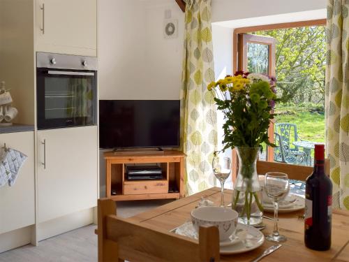 una cocina con una mesa con un jarrón de flores en Parlwr - Uk11210, en Cwrt-newydd