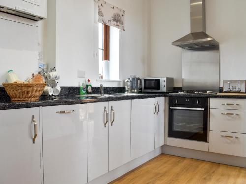kuchnia z białymi szafkami i czarnymi blatami w obiekcie Fallow Cottage - Uk33488 w mieście Hadleigh
