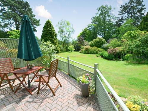Un patio con una sombrilla y una mesa y sillas. en Alices Lodge, en Ringwood