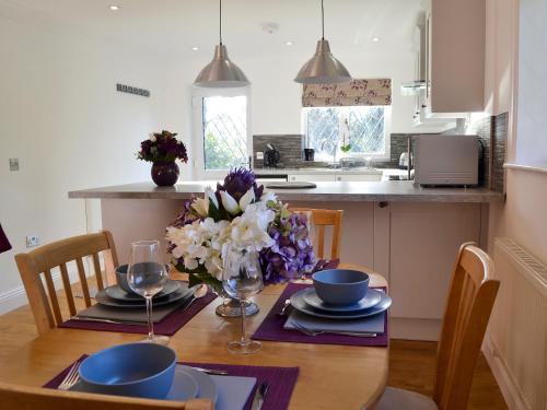 a dining room table with a vase of flowers on it at Alices Lodge in Ringwood