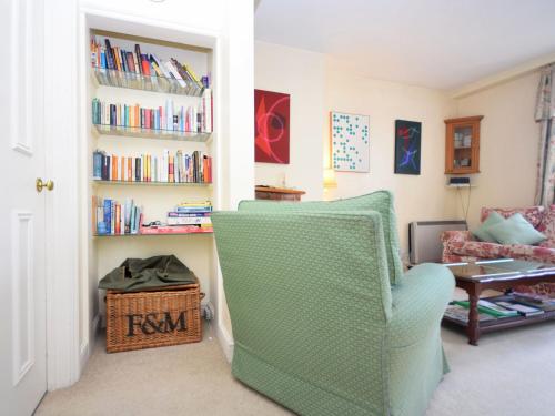 a living room with a chair and a book shelf at Pepper Pot Cottage in Compton