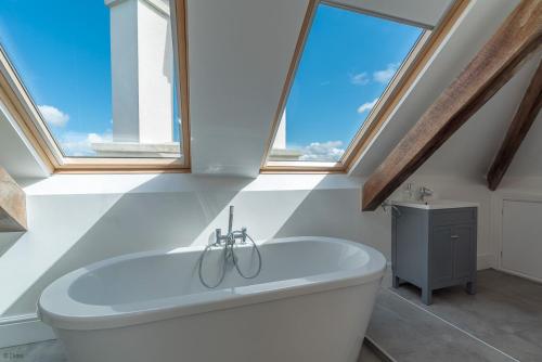 a bathroom with a white tub and windows at Bryndeusant in Llanbabo