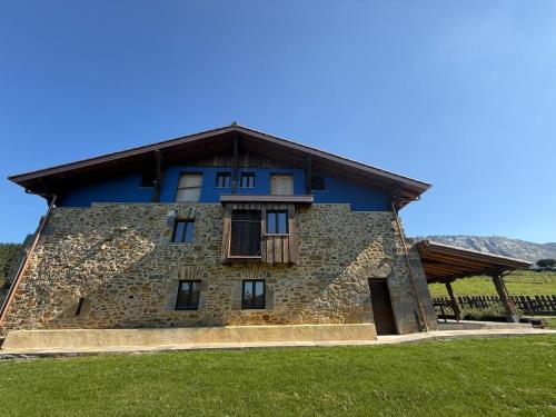 a large stone house with a blue roof at Arandi Baserria in Urigoiti