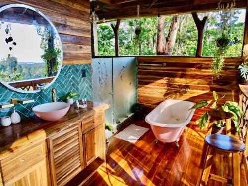a bathroom with a tub and a sink and a mirror at Jungle Spirit Treehouse in Cahuita