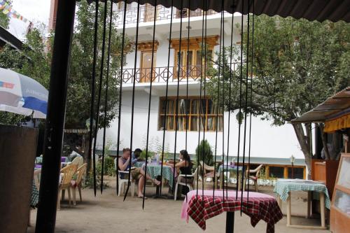 a group of people sitting at tables in front of a building at Mentokling Guest House and Garden Restaurant in Leh