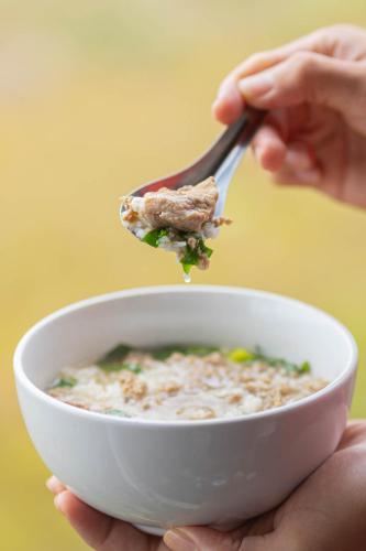 a person eating food from a bowl with a fork at KraThom Doi Luang in Chiang Dao