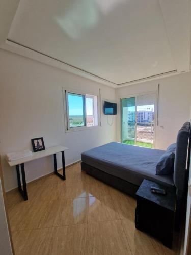 a bedroom with a bed and a table and window at APPARTEMENT DE LUXE 3 Façades in O Ben Slimane