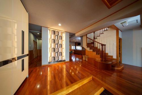 a living room with a wooden floor and stairs at クリスタルヴィラ金城 in Naha