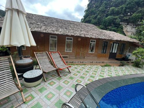 a house with chairs and an umbrella and a pool at Trang An Maison Retreat in Nguyên Ngoại