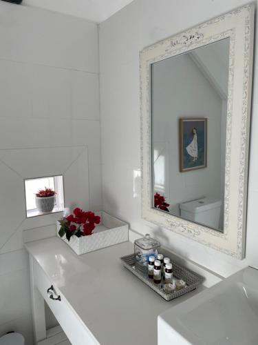 a white bathroom with a mirror and a white sink at Bougain Villa in Paternoster