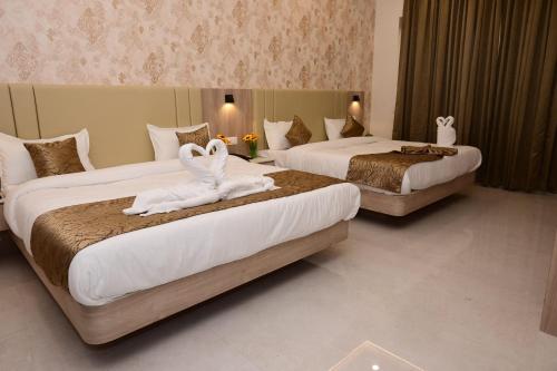 two beds in a hotel room with towels on them at Hotel Golden Palace Ayodhya in Ayodhya