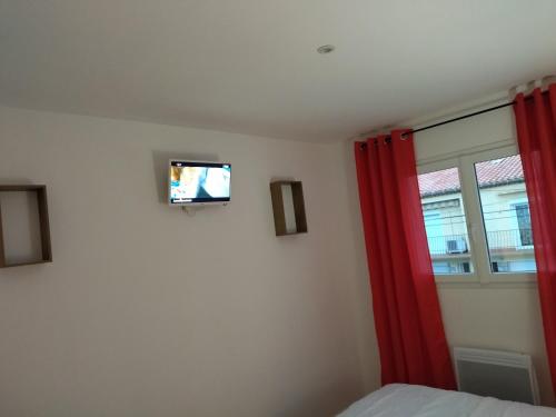 a bedroom with a bed and a tv on the wall at Appartement Amaryllis in Le Boulou