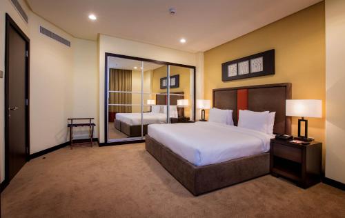 a bedroom with a large bed and a large mirror at Orange Suites Hotel in Manama