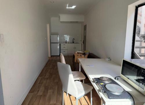 a room with a desk with a computer and chairs at Kent st Hostel in Rockhampton