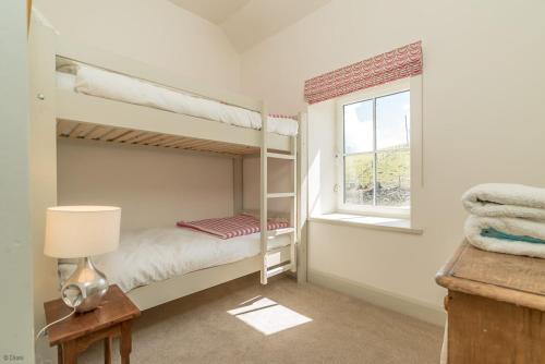 Un dormitorio con dos literas y una ventana. en Erw-Dinmael, en Cerrig-y-Druidion