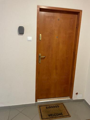 una puerta de madera con una alfombra de bienvenida delante de ella en Apartament w Centrum Faktura, en Koszalin