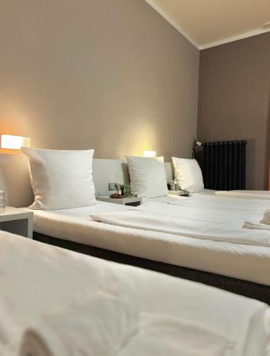 two beds in a hotel room with white pillows at Colour Hotel in Frankfurt