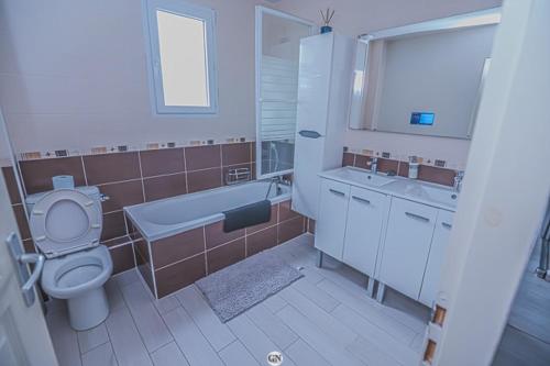 a bathroom with a toilet and a tub and a sink at Location Cosy Paris - villa Emeraude in Sainte-Geneviève-des-Bois