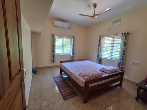 a bedroom with a bed and two windows at Satvik Life Homestay-Pure Veg,No Drinking & No Smoking in Kumta