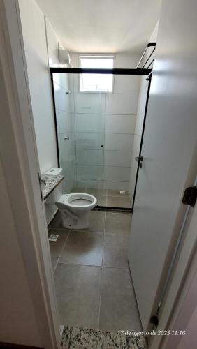 a bathroom with a toilet and a glass door at Apto em Barretos Próximo PIO XII in Barretos