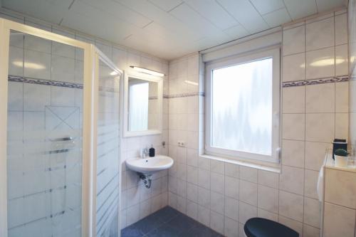 a white bathroom with a sink and a window at Küstenkind in Spieka-Neufeld