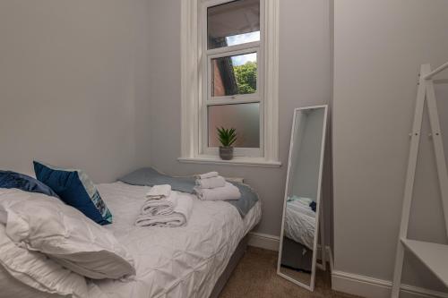 ein Bett in einem Zimmer mit einem Fenster und einem Spiegel in der Unterkunft Contractors Business Families Relocation Accommodation enjoy Fast WiFi Large Screen Smart TV and SKY Sports in this Spotless Ground Floor apartment in Wakefield