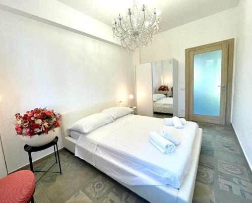 a bedroom with a large white bed and a chandelier at Hostdomus - La Rocca in Garlenda