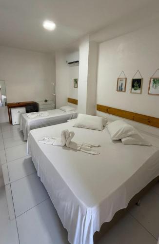 two large beds in a room with white walls at Pousada Mel in Praia do Forte