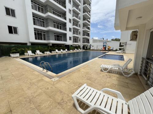 a swimming pool with white chairs and a building at Ocean waves in Mombasa