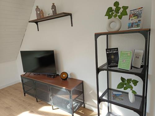 a living room with a television and a table with a shelf at Cozy apartment in Harsum near Hildesheim in Harsum
