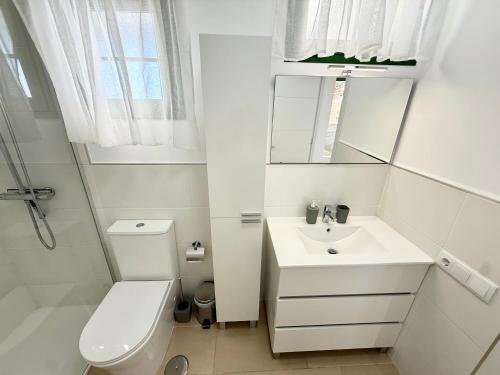 a white bathroom with a toilet and a sink at Oceanica home in Mogán