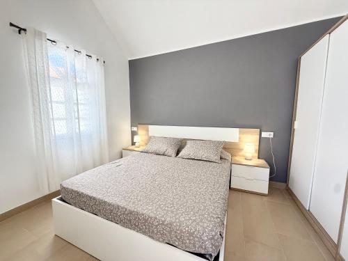 a white bedroom with a bed and two lamps at Oceanica home in Mogán