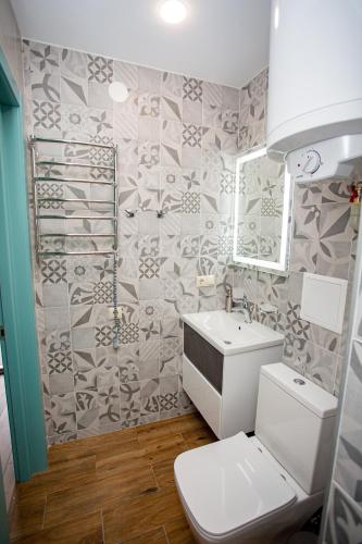 a bathroom with a toilet and a sink and a mirror at My Home Apartments in Berehove