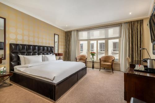 Una habitación de hotel con una cama grande y un escritorio. en Washington Mayfair Hotel, en Londres