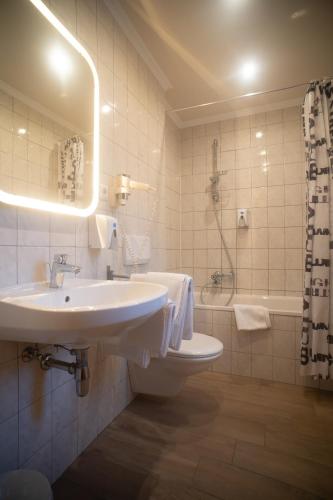 a white bathroom with a sink and a tub at Pension Wachau in Klagenfurt