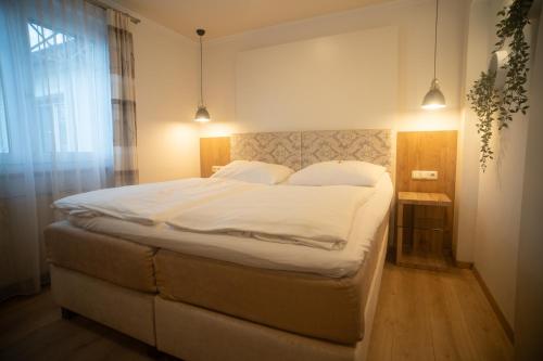 a bedroom with a large bed with white sheets at Pension Wachau in Klagenfurt