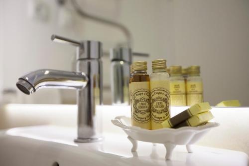 un lavabo avec deux bouteilles de liquide jaune dans un support dans l'établissement Otília Apartamentos, à Lisbonne