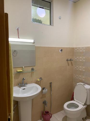 a bathroom with a sink and a toilet and a window at Skyline Rooftop Studio in Muzaffarabad